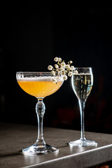 Bright cocktail garnished with flowers sits on a sleek bar, ready for enjoyment amid laughter