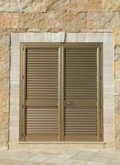 Aluminum yellow closed louvered door on sotne wall closeup