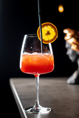 A vibrant cocktail sits elegantly in a glass, garnished with a slice of orange, ready to be enjoyed
