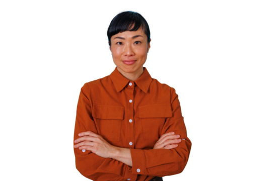 Confident asian woman smiling, arms crossed, wearing an orange shirt, standing on a transparent background