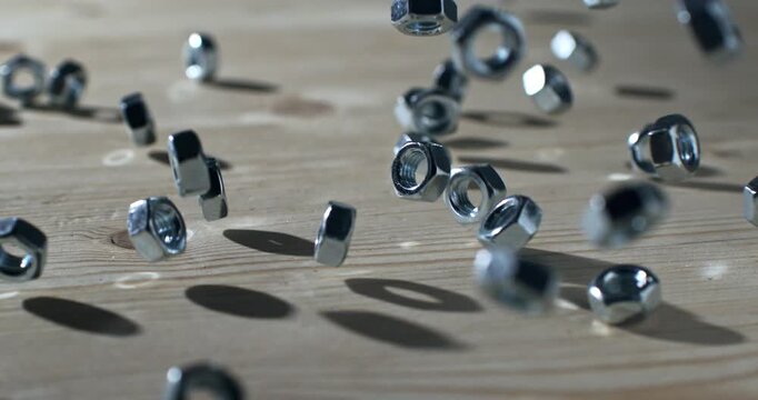 Slow Motion Shot Of Metal Nuts Bouncing On A Wooden Surface With Strong Shadows And Industrial Impact At 1000 Fps. Concept Of Precision And Motion
