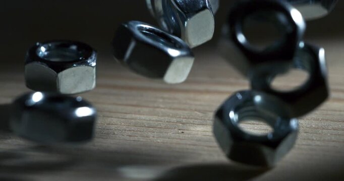 Slow Motion Macro Shot Of Metal Nuts Bouncing On A Wooden Surface With Strong Shadows And Industrial Impact At 1000 Fps. Concept Of Precision And Motion
