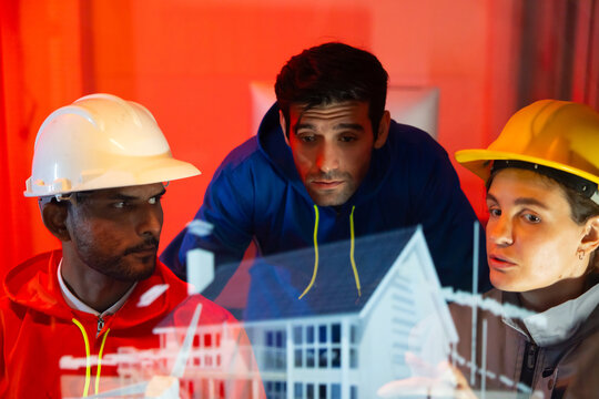 Modern construction and engineering Team Collaborating on Futuristic Holographic Interface Analyzing. Holographic Technology for Innovative house Development Planning