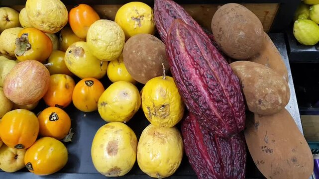 Horizontal above view of persimmon, passion fruit, cacao pod and cupua&ccedil;u  on grocery store.
