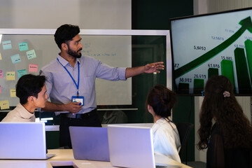 Business team analyzing data on laptops with growth chart in background. Diverse professionals collaborating in office, discussing financial performance, strategy, and success analytics in  workplace.