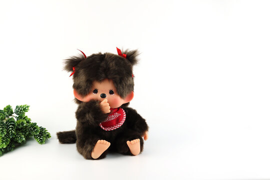 a popular classic doll toy , Monchichi or Monchhichi , Japanese cute monkey fur doll display on white table with white wall background in souvenir tourist shop in Japan