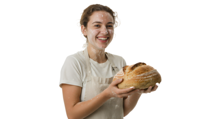 A young artisan baker covered in flour smiling and holding a loaf of fresh bread