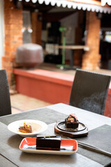 A shot of tiramisu, dark chocolate brownie, and sizzling brownie placed together on a table, served in white plates with a softly blurred restaurant ambiance in the background 