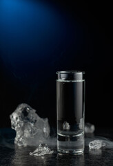 Crystal clear vodka or gin in a glass on a black stone table.