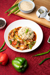 Calcutta chilli chicken with fried rice served on a white plate, styled with sliced capsicums, fresh green chillies, raw rice and black pepper for a vibrant Indo-Chinese food presentation.