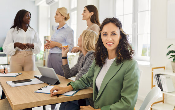 Woman portrait leads team meeting in office. A diverse group collaborates, planning strategy and training goals, building leadership and teamwork. Concept: women leadership strategy teamwork.