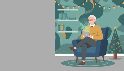 Senior man relaxing with a tablet by the Christmas tree enjoying modern retirement