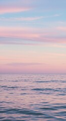 Obraz premium Calm ocean with pink and blue sunset sky and subtle ripples on the water surface