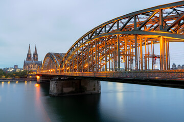 Historic Cologne Cathedral and Hohenzollern Bridge at Twilight. The Hohenzollern bridge over the Rhine river with the Cologne Cathedral rising in the background at twilight. Germany.
