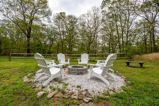 White Adirondack Chairs Around Stone Fire Pit