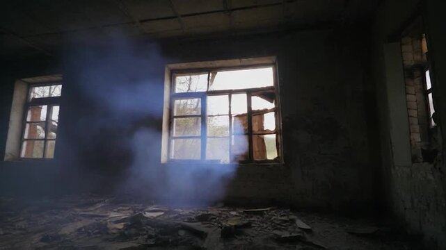 Eerie atmosphere inside derelict structure with smoke illuminated by sunlight through broken windows