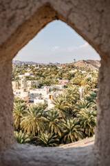 Arch framing traditional omani mountain village with date palm trees
