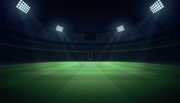 Illuminated football stadium at night with grass field, goal post, and spotlight beams.