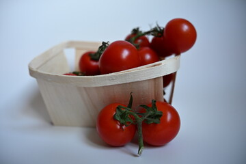 Clean and bright composition focusing on the farm fresh quality of tomatoes. Rustic basket contrasts with the minimalist white background, ideal for packaging design.