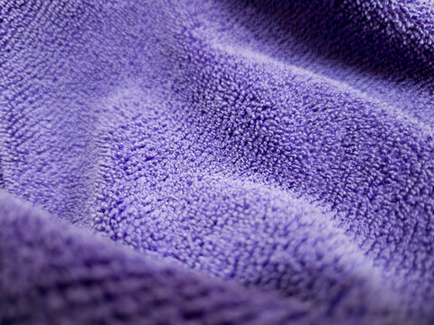 Purple Towel: An up-close shot showcases the soft, textured surface of a plush, purple towel, the fabric folds creating a pattern of shadows and highlights.