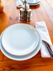 served wooden table top withe empty white plates