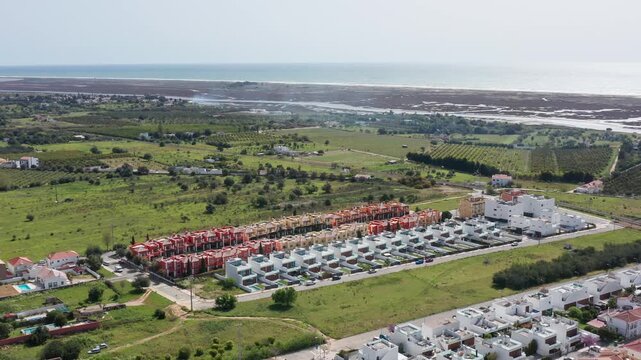 Uniform residential housing stretching across coastal landscape, revealing systematic urban development and expansive suburban growth near oceanfront region.Tavira, Portugal Fuzeta.