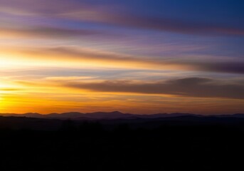 A peaceful landscape silhouette against the dramatic golden hour sky, capturing the serenity of twilight as dusk settles over the horizon, atmosphere, peaceful, landscape