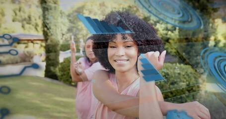 Front woman initiating crossbody stretching leading mirroring on lawn, blue HUD guiding fitness
