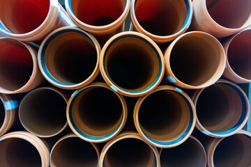 Cylindrical brown paper rolls stacked closely together in a well-lit storage area during the day