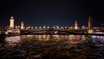 Obraz premium Wide night view of Pont Alexandre III with golden illumination and Seine reflections.