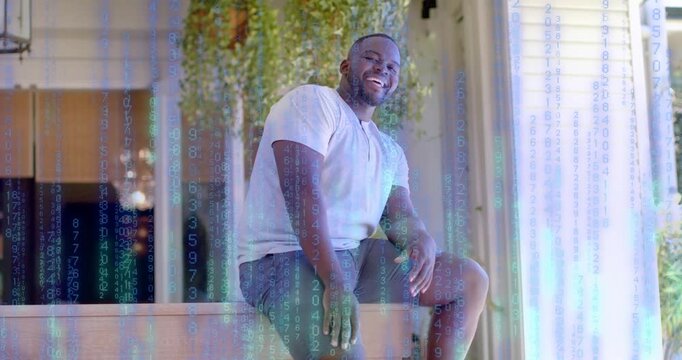 Man sitting on low ledge, shifting, laughing, showing tech code overlay rising, masking then fading