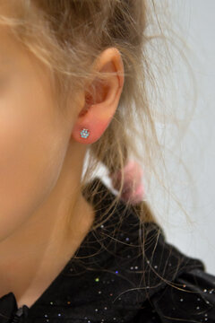 Girl's ear with a flower-shaped earring. A closeup of a beautiful piercing on a child.