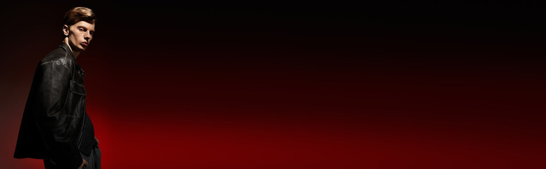 Young man embodies modern masculinity with style and allure in striking red backdrop