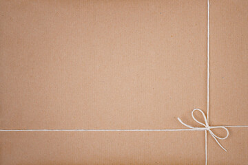 White String Twine Tied in Bow on Kraft Paper Background