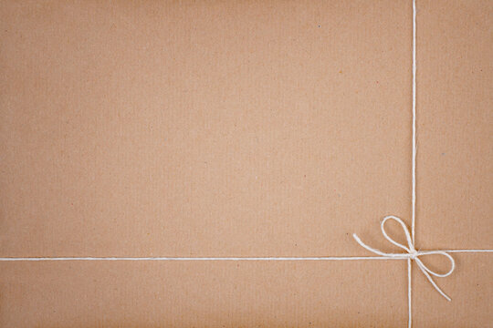 White String Twine Tied in Bow on Kraft Paper Background