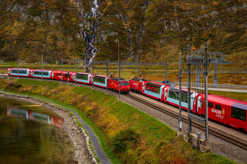 View of the Glacier Express train at Lake Oberalp in the Alps near Andermatt in Switzerland.