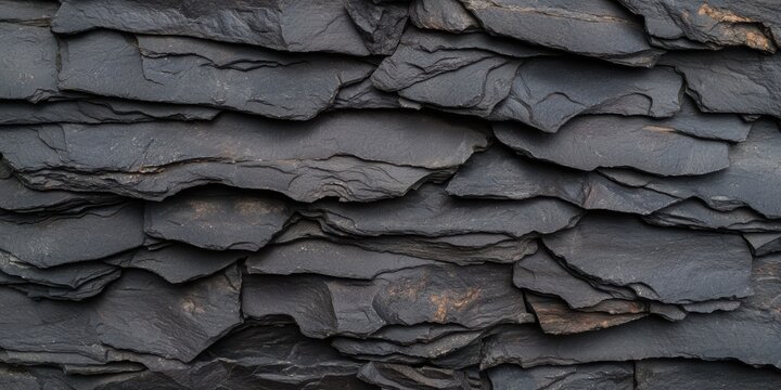 A close-up view of layered black slate stone, showcasing its rough texture and natural patterns.