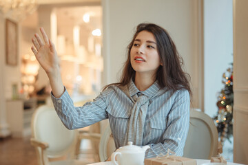 Young girl calling the waitress in cafe