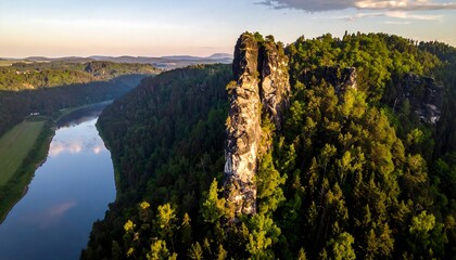 Solitary rock spire above river with mountain backdrop