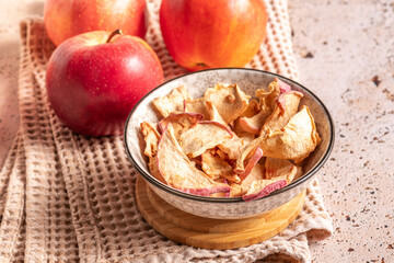 Dried apple slices in ceramic bowl. Sun-dried natural apple slices on a beige kitchen table background. Healthy snack
