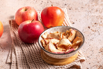 Dried apple slices in ceramic bowl with fresh apples on a beige napkin. Sun-dried natural apple slices on a beige kitchen table background. Healthy snack