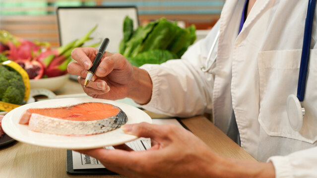Male dietitian sitting at desk with different healthy products and writing diet plan, Healthy life style concept, doctor writing, diet and losing weight