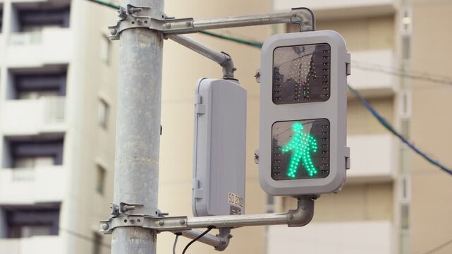 Slow motion capture of pedestrian signals mounted on a red wall building changing from red to green, urban flow suited for mobility and safety themes