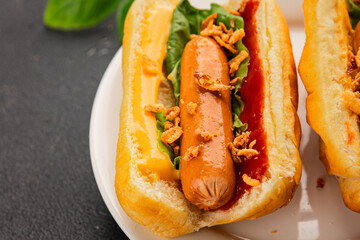 Hotdog fried onions, sausage, bun, sauce fast food tasty snack fresh delicious gourmet food background on the table rustic top view copy space