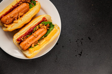 Hotdog fried onions, sausage, bun, sauce fast food tasty snack fresh delicious gourmet food background on the table rustic top view copy space