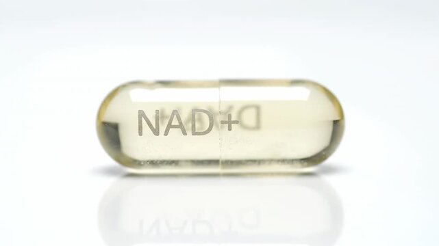 Close up of a rotating transparent yellow NAD plus supplement capsule filled with nicotinamide adenine dinucleotide, highlighting longevity, metabolism support and antioxidant benefits