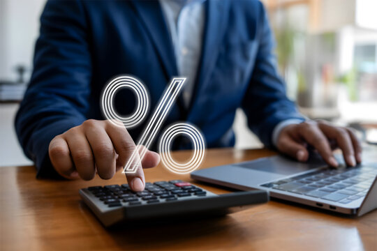 Businessman calculating interest rates using a calculator with a glowing percentage sign.