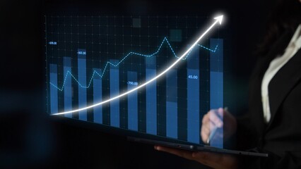 A professional businesswoman analyzes data on a laptop, showcasing a bar chart with an upward...