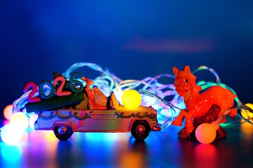 A toy car with Santa Claus and the date 2026. There is a glowing Christmas tree garland and a horse figurine nearby.