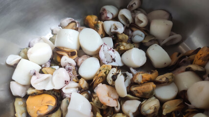 Close-up of raw fish and shellfish on a plate. It evokes natural freshness, quality ingredients, and gourmet preparation.